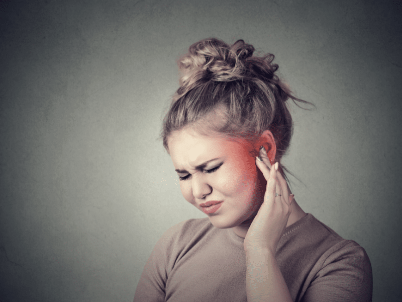 Young woman holding her ear in pain.